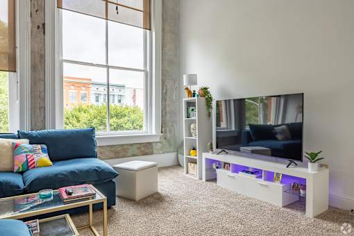 A living room with a blue couch, a coffee table, a TV, and a window.