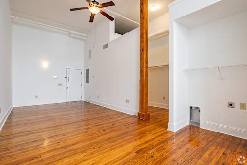 A room with a ceiling fan and wooden floors.