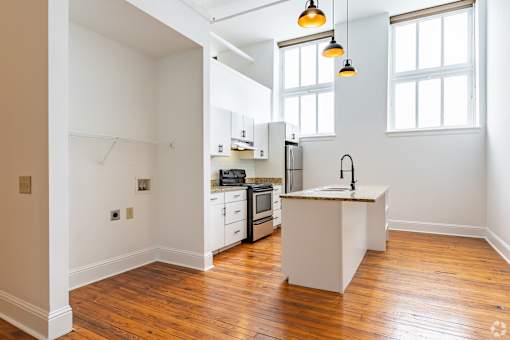 A kitchen with white cabinets and a wooden floor.
