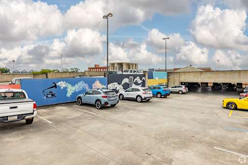 A parking lot with cars and a mural on the wall.
