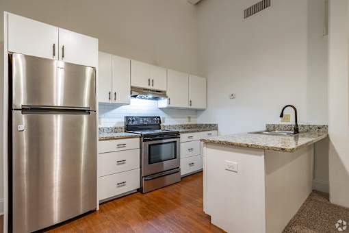 A kitchen with a stainless steel refrigerator, microwave, oven, and cabinets.