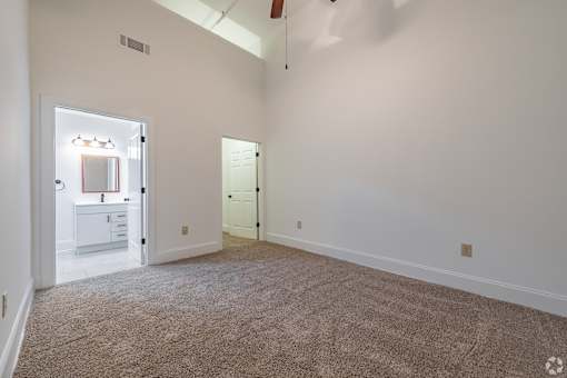 A room with a carpeted floor and a ceiling fan.