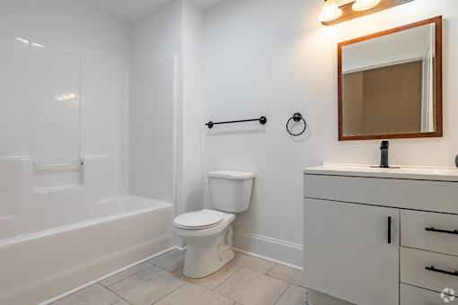 A white toilet sits in a bathroom next to a bathtub.