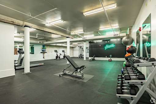 A gym with a variety of equipment including treadmills, weights, and a bench press.