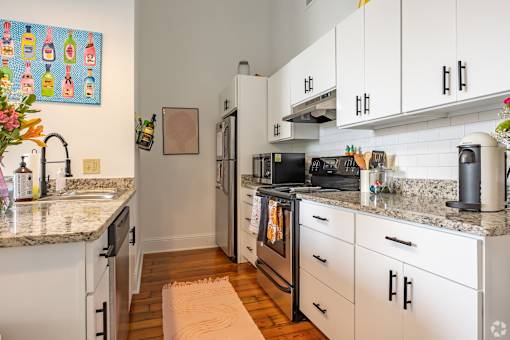 A kitchen with white cabinets and granite countertops.