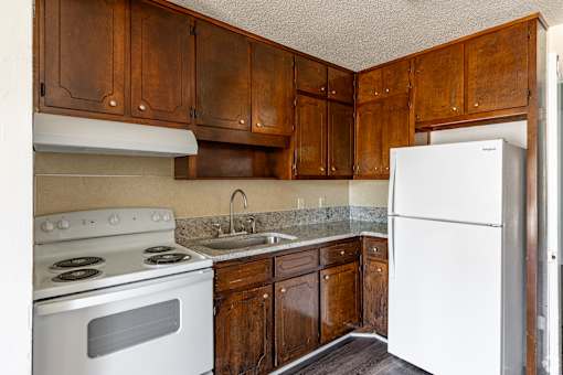A kitchen with white appliances and wooden cabinets.