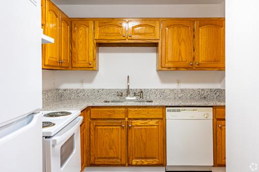 A kitchen with wooden cabinets and a white dishwasher.
