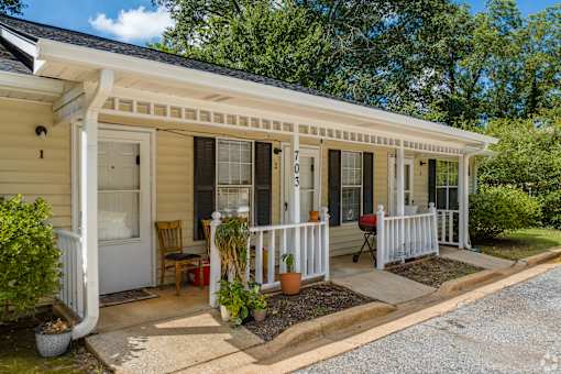 A small house with a porch and a white railing.