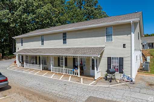 A white building with a porch and a bicycle parked in front.