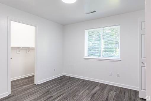 A room with a window and a wooden floor.