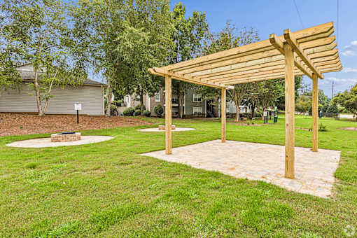 A wooden pergola stands over a grassy area.