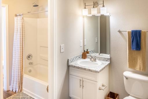 A bathroom with a white toilet, sink, and shower.