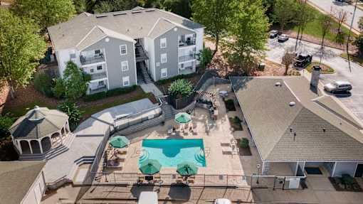 An aerial view of a pool surrounded by a gazebo and apartment buildings.