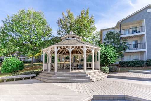 A gazebo is surrounded by a wooden deck and steps.