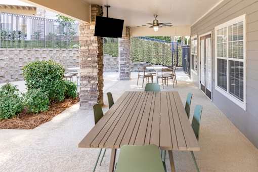A patio with a table and chairs and a TV on the wall.