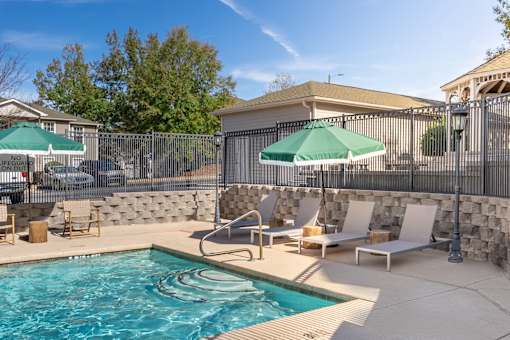A pool with a stone wall and a fence.