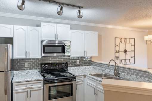 A kitchen with white cabinets and a black stove top oven.