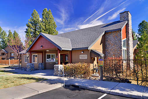 A building with a brown roof and a sign that says "CENTER" is surrounded by a fence and trees.
