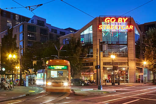 A streetcar is passing by a building with a neon sign that says "GO BY STREETCAR".