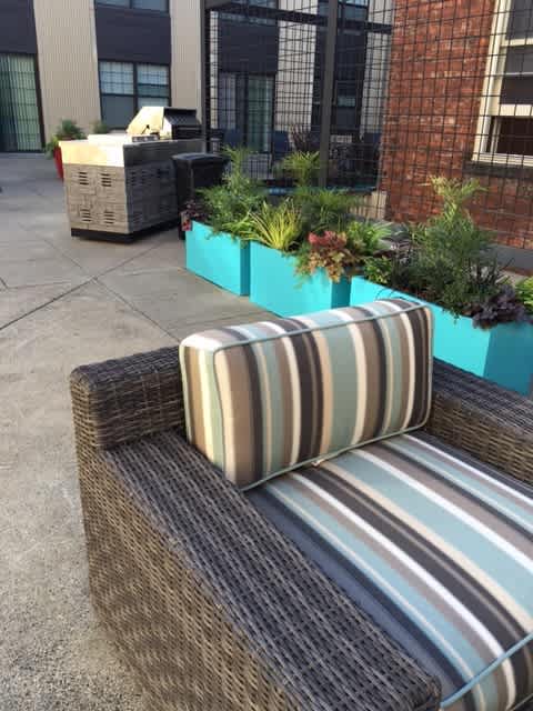 A striped cushion is on a wicker sofa.
