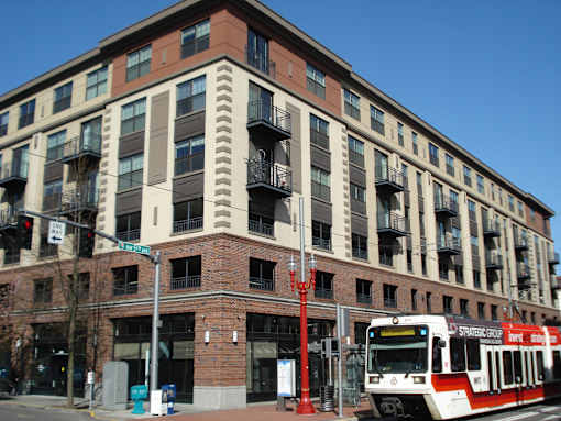 A red and white train is on the tracks in front of a building.