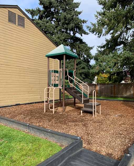 A playground with a green roof and a slide.