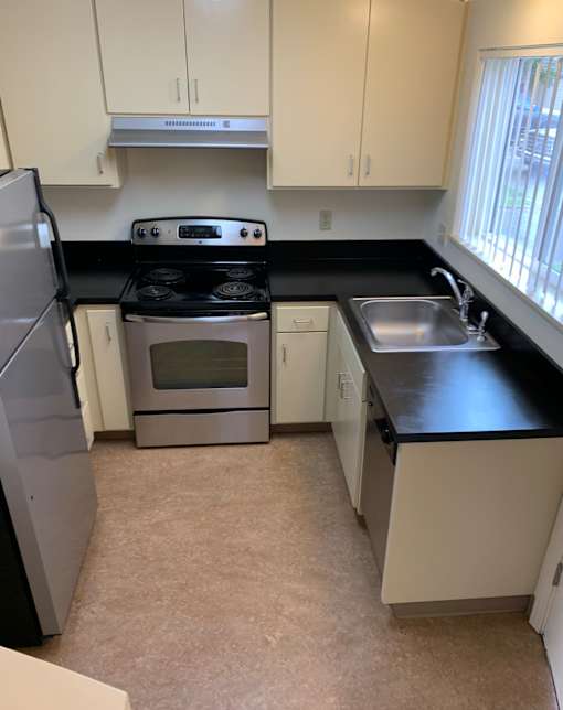 A kitchen with white cabinets and black countertops.