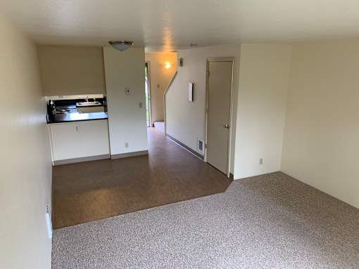 A room with a carpeted floor and a door leading to another room.