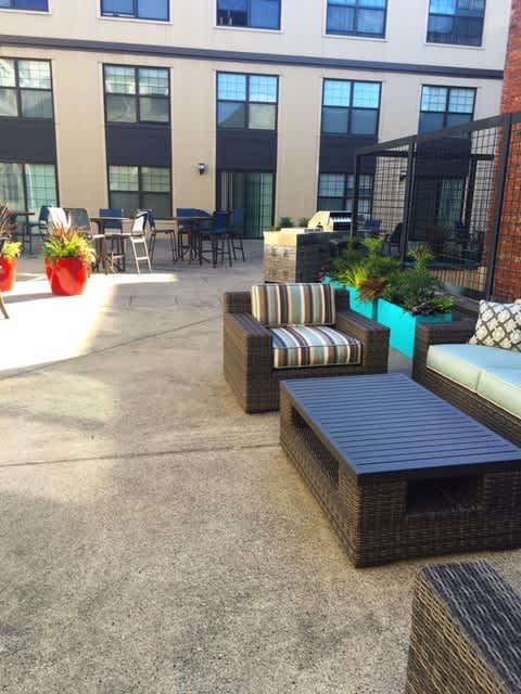 A patio with a black wicker sofa and a black metal fence.