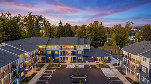 A large apartment complex with a parking lot in front.