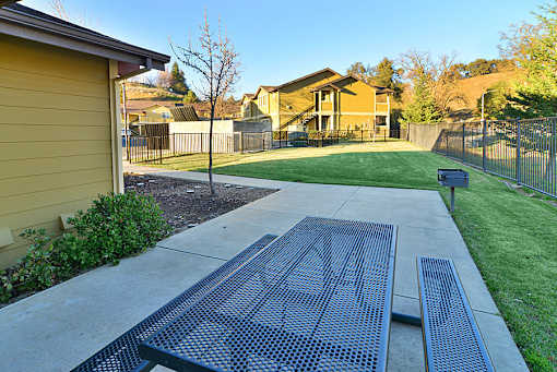 A residential area with a yellow house and a metal bench.