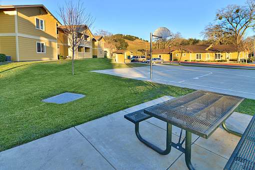 A basketball court with a hoop and a bench in the foreground.