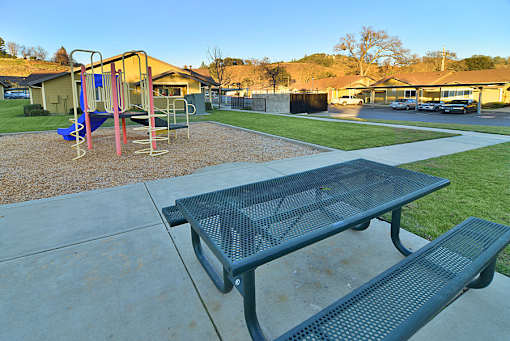 A playground with a slide and a picnic table.