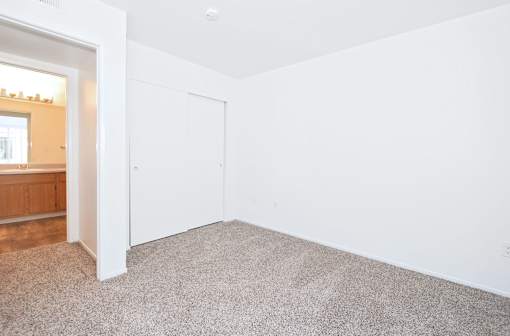 A white room with a carpeted floor and a white door.