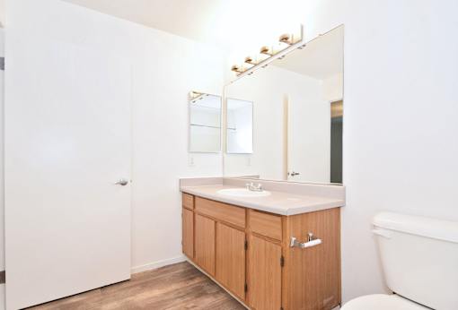 A white bathroom with a wooden cabinet and a white tub.
