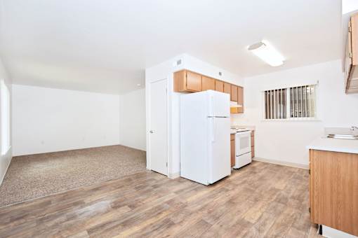 A kitchen with white appliances and wooden floors.