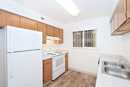 A kitchen with white appliances and wooden cabinets.