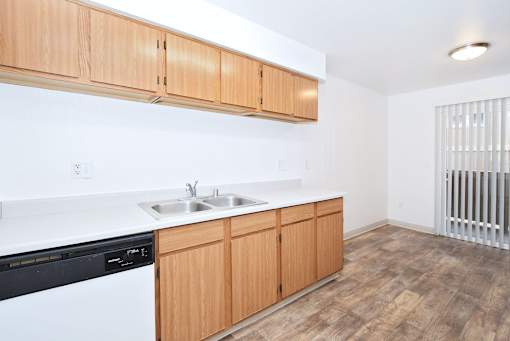A kitchen with wooden cabinets and a black dishwasher.