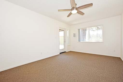 Empty room with a ceiling fan and carpeted floor.
