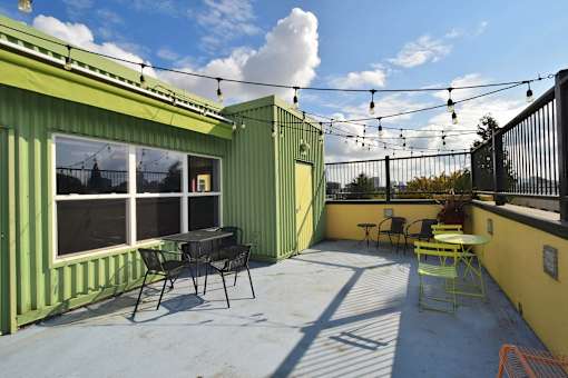 A patio with a table and chairs is surrounded by green walls.