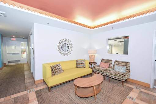 A living room with a yellow couch and a wooden coffee table.