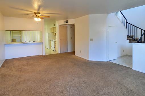 A room with a carpeted floor and a ceiling fan.