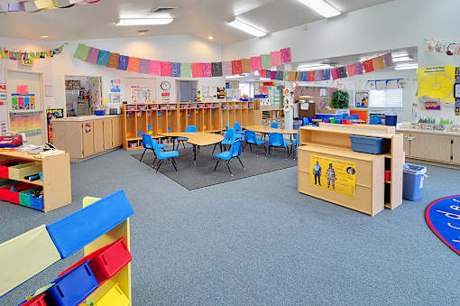 A classroom with tables and chairs and a blue carpet.