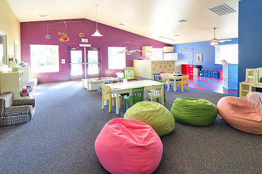 A room with a purple wall and a carpeted floor with bean bag chairs.