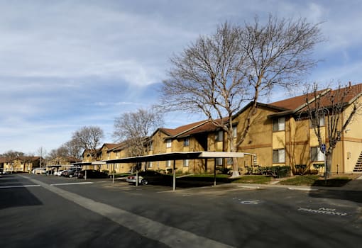 Apartment complex with a parking lot in front.