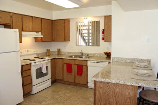 A kitchen with a white refrigerator, wooden cabinets, and a marble countertop.
