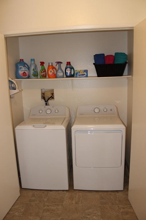 A white microwave oven is installed above a white refrigerator.