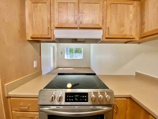 A kitchen with wooden cabinets and a stove top oven.