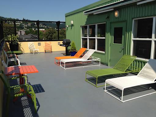 A patio with a green building and white furniture.