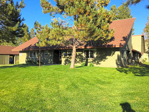 A house with a brown roof and a green lawn.